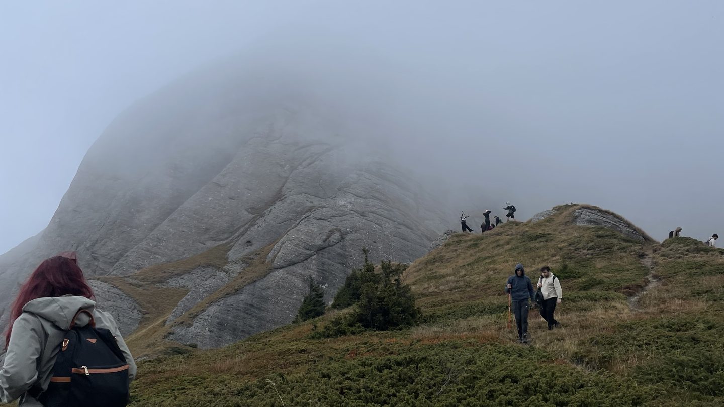 Hikers climbing a foggy mountain ridge