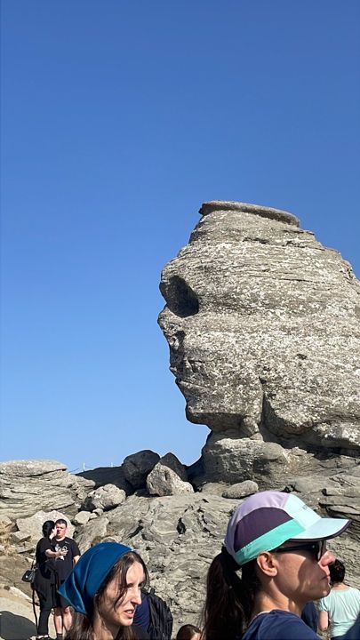 Two people in front of a large rock formation in the mountains