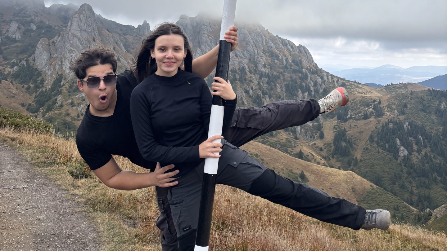 Two friends having fun at a trail sign in the mountains
